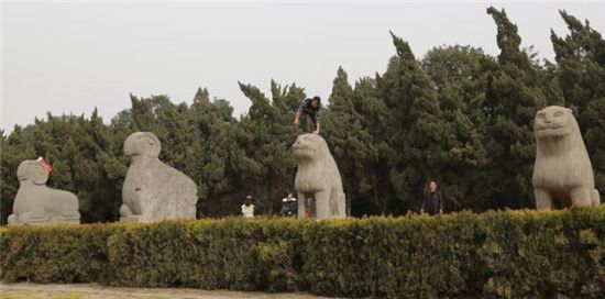 景区多名游客脚踩千年文物拍照留念(图)